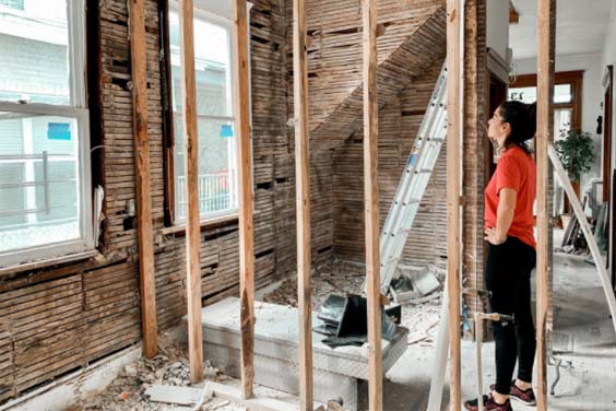 A woman standing in a room with stripped walls