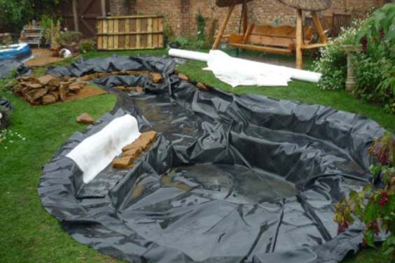 Pond liner spread out and secured using rocks